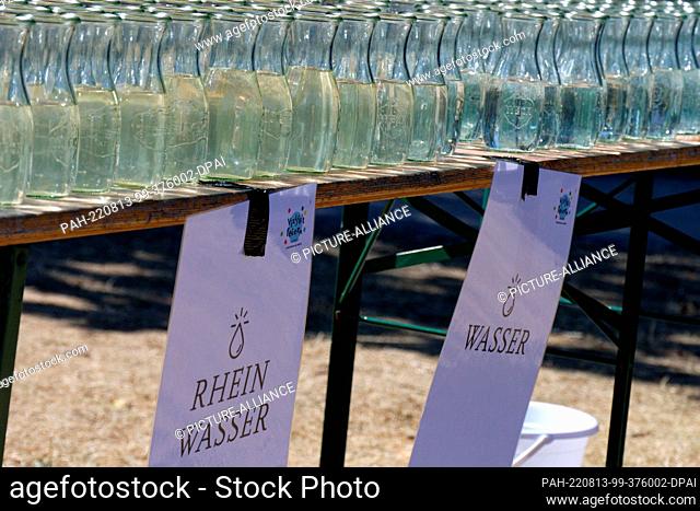 13 August 2022, North Rhine-Westphalia, Cologne: Bottles of water from the Rhine and tap water are ready for baptism at the baptism festival of the Protestant...