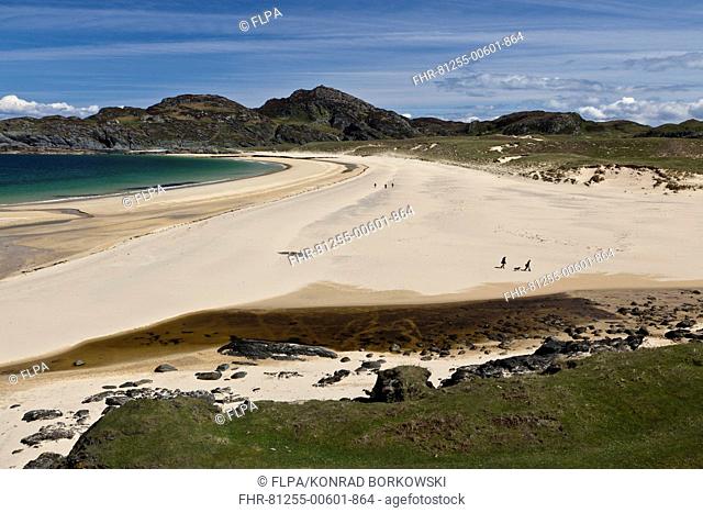 View of coastline with people walking on sandy beach, Kiloran Bay, Isle of Colonsay, Inner Hebrides, Scotland