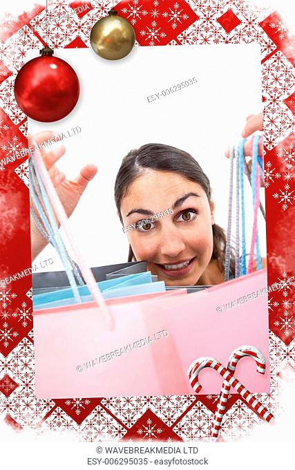 Portrait of a cheerful woman showing shopping bags against christmas themed page