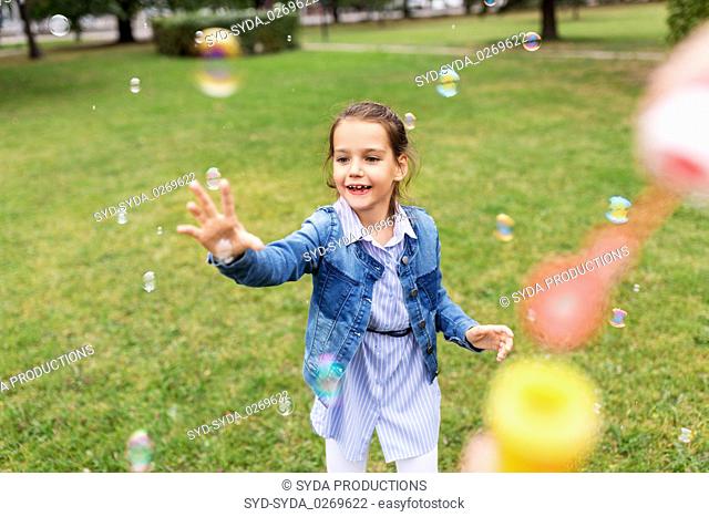 happy girl playing with soap bubbles at park