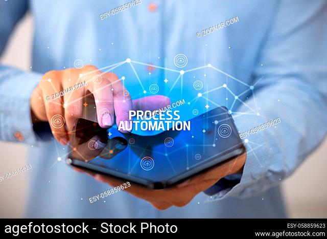 Businessman holding a foldable smartphone with PROCESS AUTOMATION inscription, new technology concept