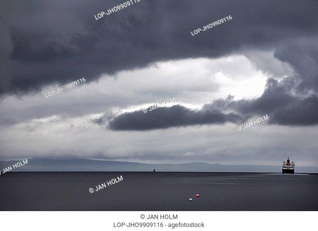 Scotland, North Ayrshire, Isle of Arran, Stormy skies over The MV Caledonian Isles, a ferry that operates between Ardrossan on the Ayrshire coast and Brodick on...