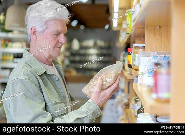 Senior man buying groceries in a small food store