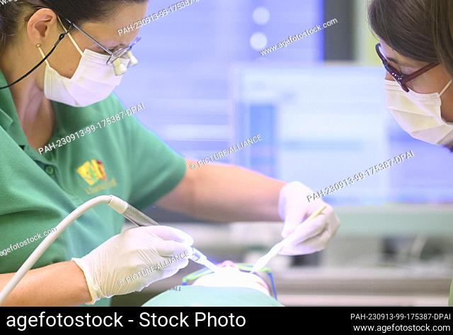 PRODUCTION - 11 September 2023, Lower Saxony, Hanover: A pediatric dentist (l) and a pediatric dental assistant examine a three-year-old child in a pediatric...