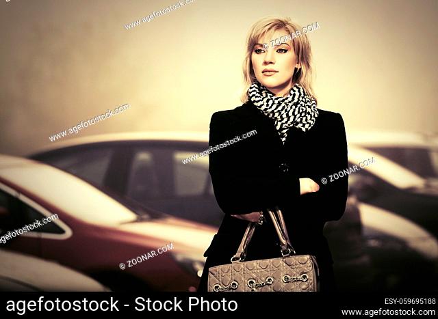 Young fashion woman with handbag in a fog on city street