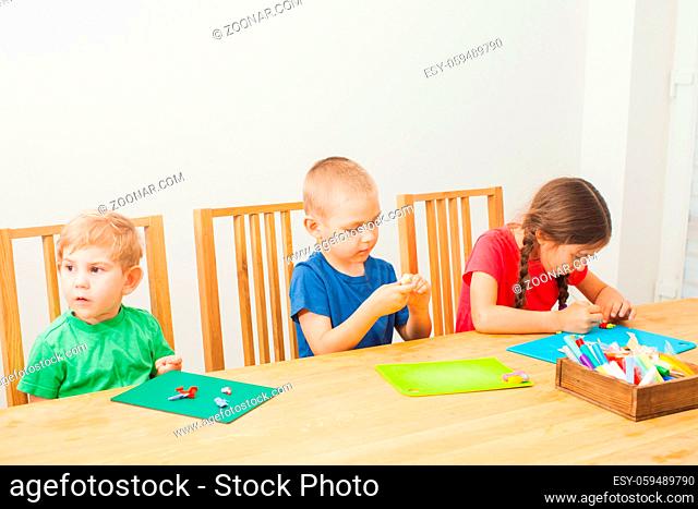 Two cute little brother and sister having fun together with colorful modeling clay at a daycare. DIY kids with cold porcelain