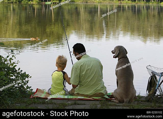 Father and son fishing with Weimaraner, angler