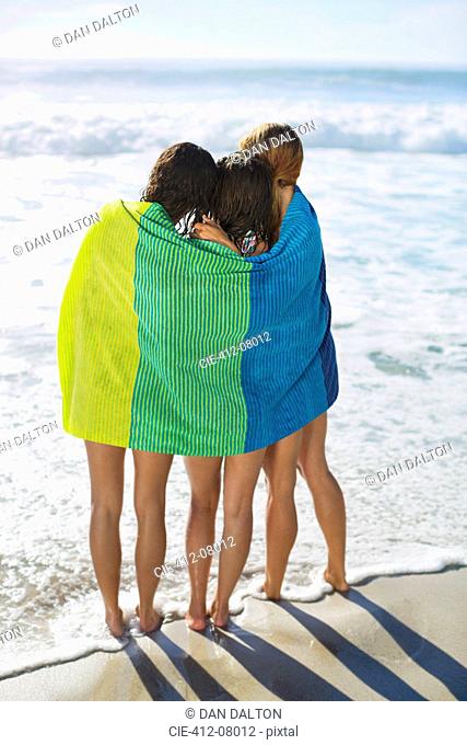 Friends wrapped in towel on beach