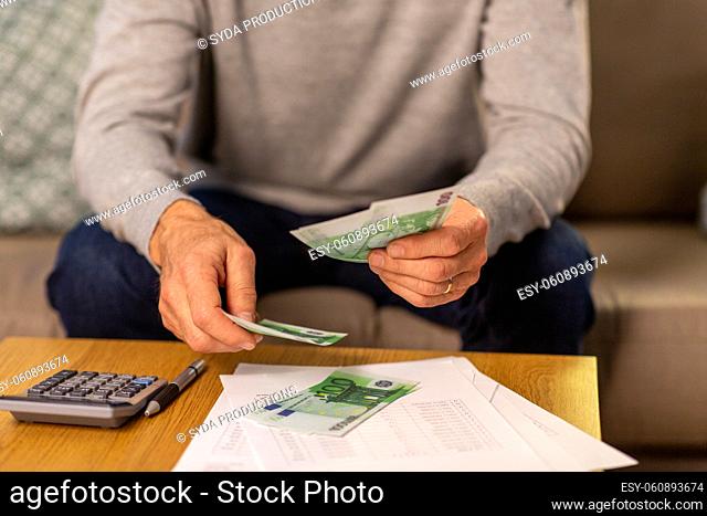 senior man counting money at home