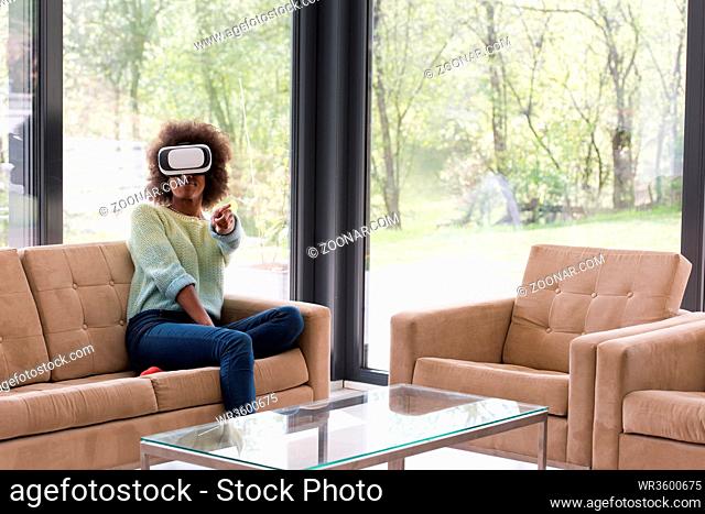 Happy african american girl getting experience using VR headset glasses of virtual reality at home