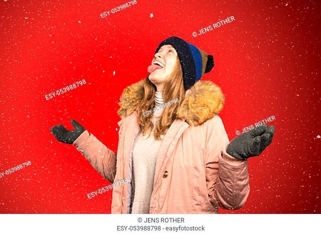 a young woman tries to catch snowflakes with her mouth