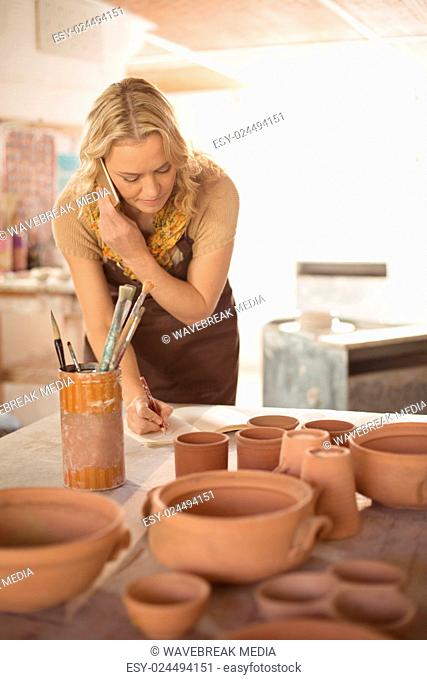 Female potter taking an order on mobile phone