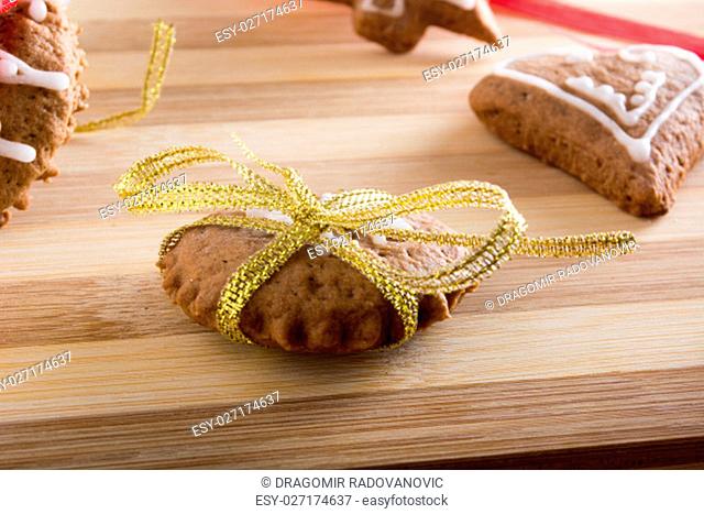Decorating gingerbread cookies with colourfull ribbons on wooden plate