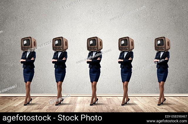 Business women in suits with old TV instead of their heads keeping arms crossed while standing in a row in empty room with gray wall on background