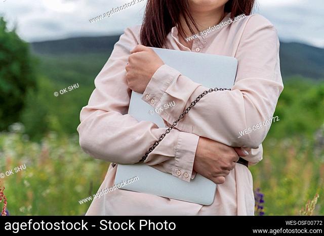 Freelancer chained with laptop in meadow