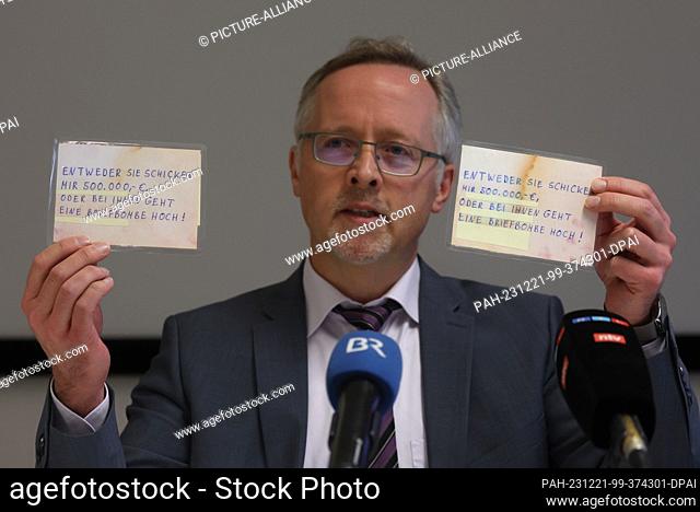 21 December 2023, Bavaria, Kempten: Josef Ischwang, head of the Kempten criminal investigation department, holds two postcards from a blackmailer at a press...