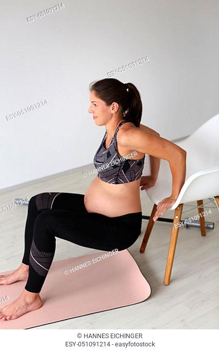 beautiful, young pregnant woman with black hair doing fitness exercises in a modern apartment, Tulln, Lower Austria