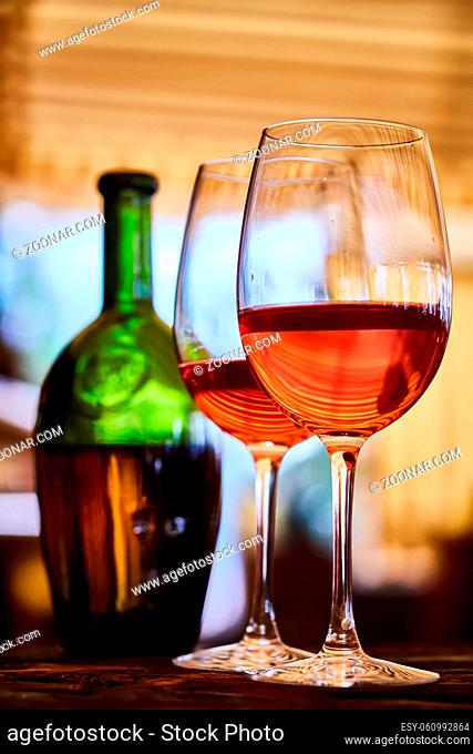 two wine glasses filled with red wine and wine bottle in background. Soft focus