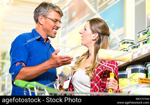 Home improver couple, woman and man, buying paint and painter tools for do-it-yourself project in hardware store