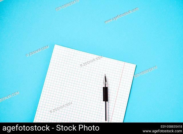 Top view of blank school paper with pen on blue background. High quality photo