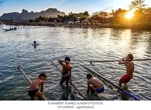 Asia. South-East Asia. Laos. Province of Vang Vieng. Vang Vieng. Boys playing in the Nam Song river at sunset