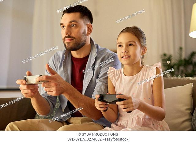 father and daughter playing video game at home
