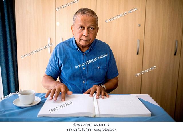 Senior man sitting with book and coffee cup at table