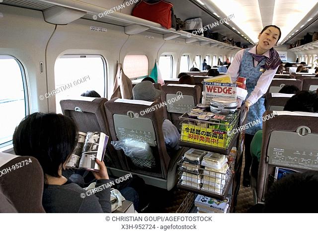 man reading manga in Shinkansen express train, mini-bar, Japan