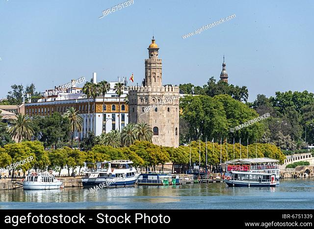 View over the river Rio Guadalquivir on promenade with excursion boats and Torre del Oro, Sevilla, Andalusia, Spain, Europe