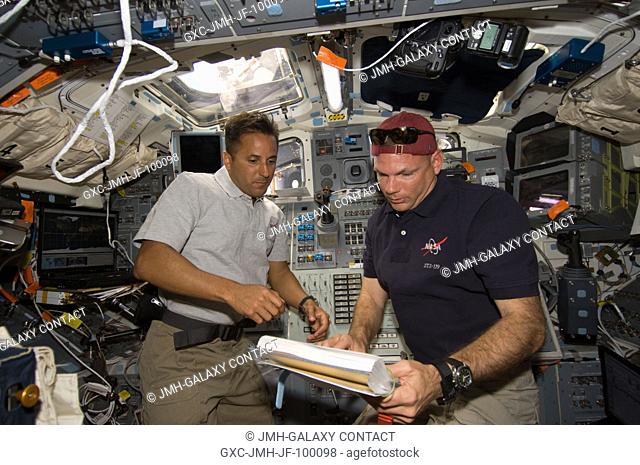 Astronauts Tony Antonelli (right), STS-119 pilot, and Joseph Acaba, mission specialist, look over a procedures checklist on the aft flight deck of Space Shuttle...