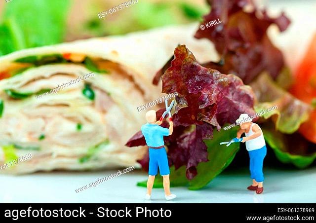 Tiny people cutting salad