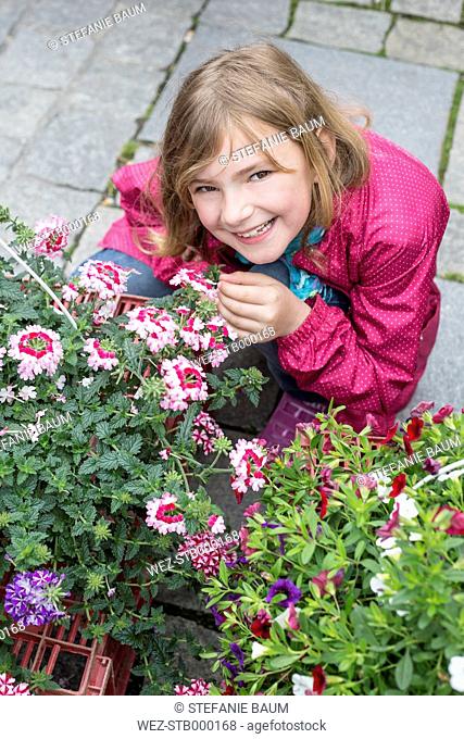 Little girl sniffing at flowers on weekly market