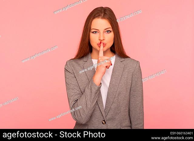Shh, keep calm. Portrait of young woman in business suit keeping finger on lips making silence gesture, shushing asking to be quiet, secrecy concept