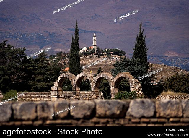 View to a old mosque on a hill from the Great Palace of Umayyad Palace with blue sky and mountainrange in the background at Anjar in Lebanon