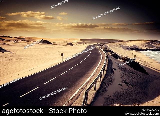 Car and drive in scenic place and long road in the middle of the desert - travel adventure concept in beautiful outdoor nature - beach and warm cloudy sky in...