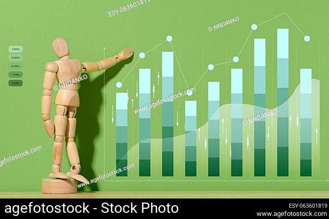 Wooden mannequin and graph with growing indicators on a green background. Analysis of financial indicators in business, income growth