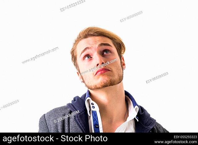 Attractive young man thinking, looking up with hand on his chin, isolated on white background, with doubtful expression