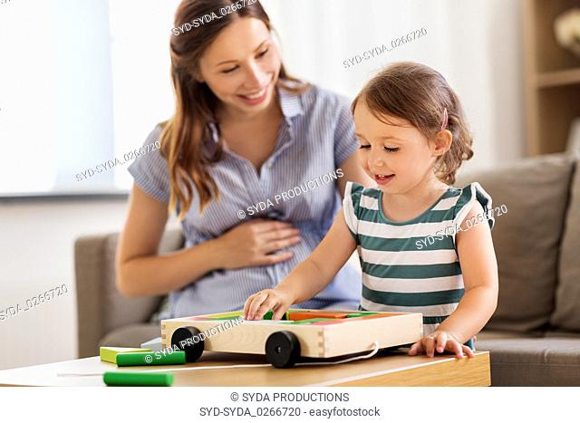 pregnant mother and daughter with toy blocks