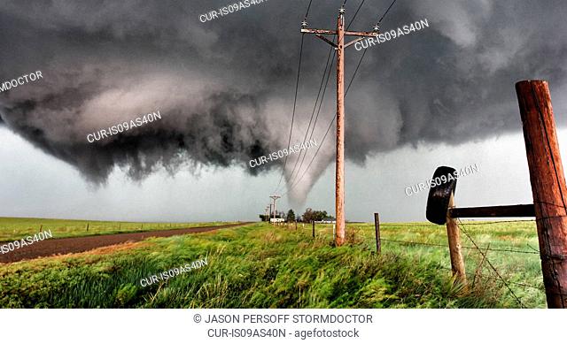 Tornado behind farmhouse with angry, violent rotating wall cloud, Stratton, Colorado, USA