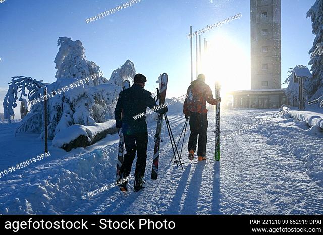 10 December 2022, Hessen, Willingen: Two skiers carry their skis on the Ettelsberg. Cold, snow and artificial snow make for an early start to the winter season