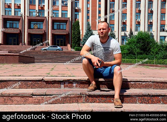 09 July 2021, Moldova, Tiraspol: Andrej, a tourist guide from Transnistria, sits in front of the parliament building in Tiraspol