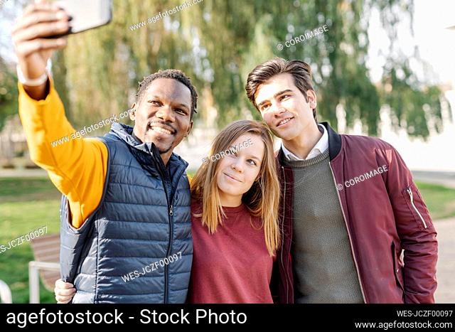 Smiling friends taking a selfie in park