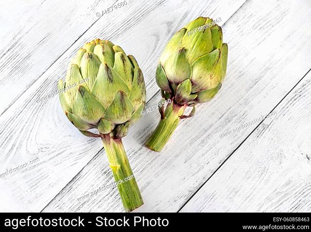 Two uncooked artichokes on the wooden table