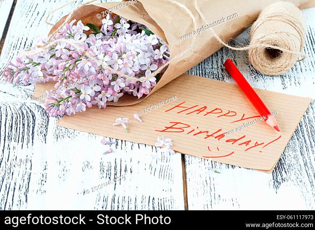 Lilac flowers with empty tag on a old wooden background