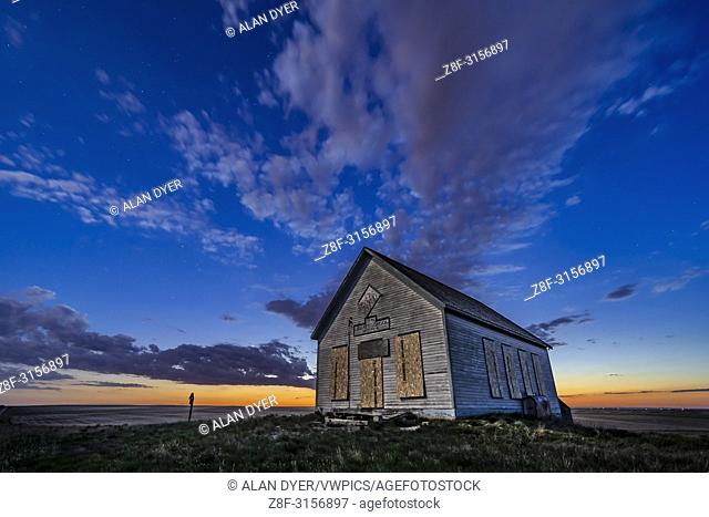 The 1910 Liberty Schoolhouse, a classic pioneer one-room schoolhouse on the Alberta prairie, at sunset as the stars are appearing