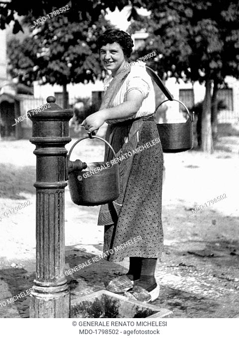 A farmer of Carnia fills a bucket with water at a fountain during the military assault on Piave against the Austro-Hungarian Empire