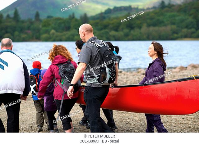 Group of people taking canoe out on lake, Cumbria, UK
