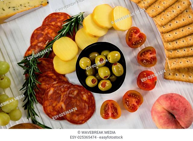 Variety of cheese with grapes, olives, salami, and crackers
