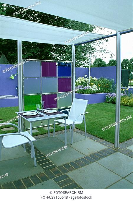 Metal table and chairs in modern gazebo in country garden