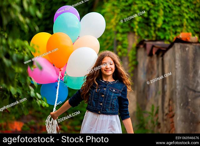 Pretty girl with big colorful balloons walking downstairs in old town